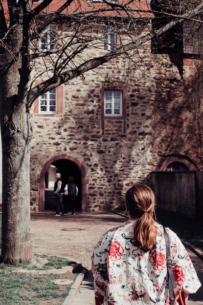 Woman with red hair walking through the city walls of Michelstadt.