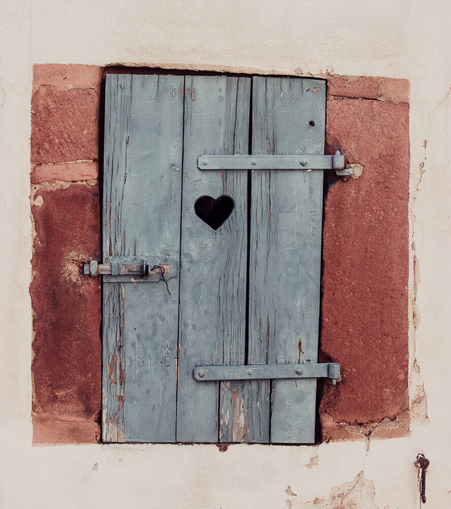 A blue wooden door with a heart shape cut out from it