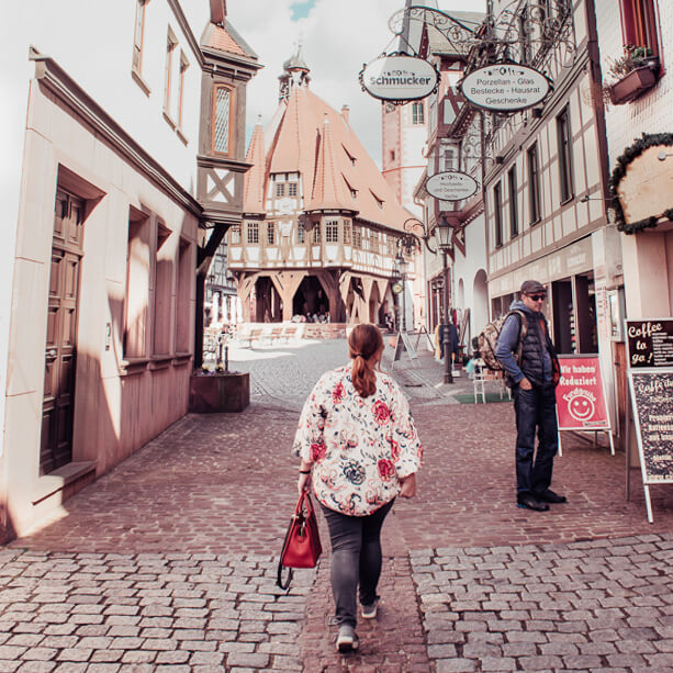 Woman wearing a floral top and jeans walking along the picturesque cobbled streets of Michelstadt in Odenwald Germany.