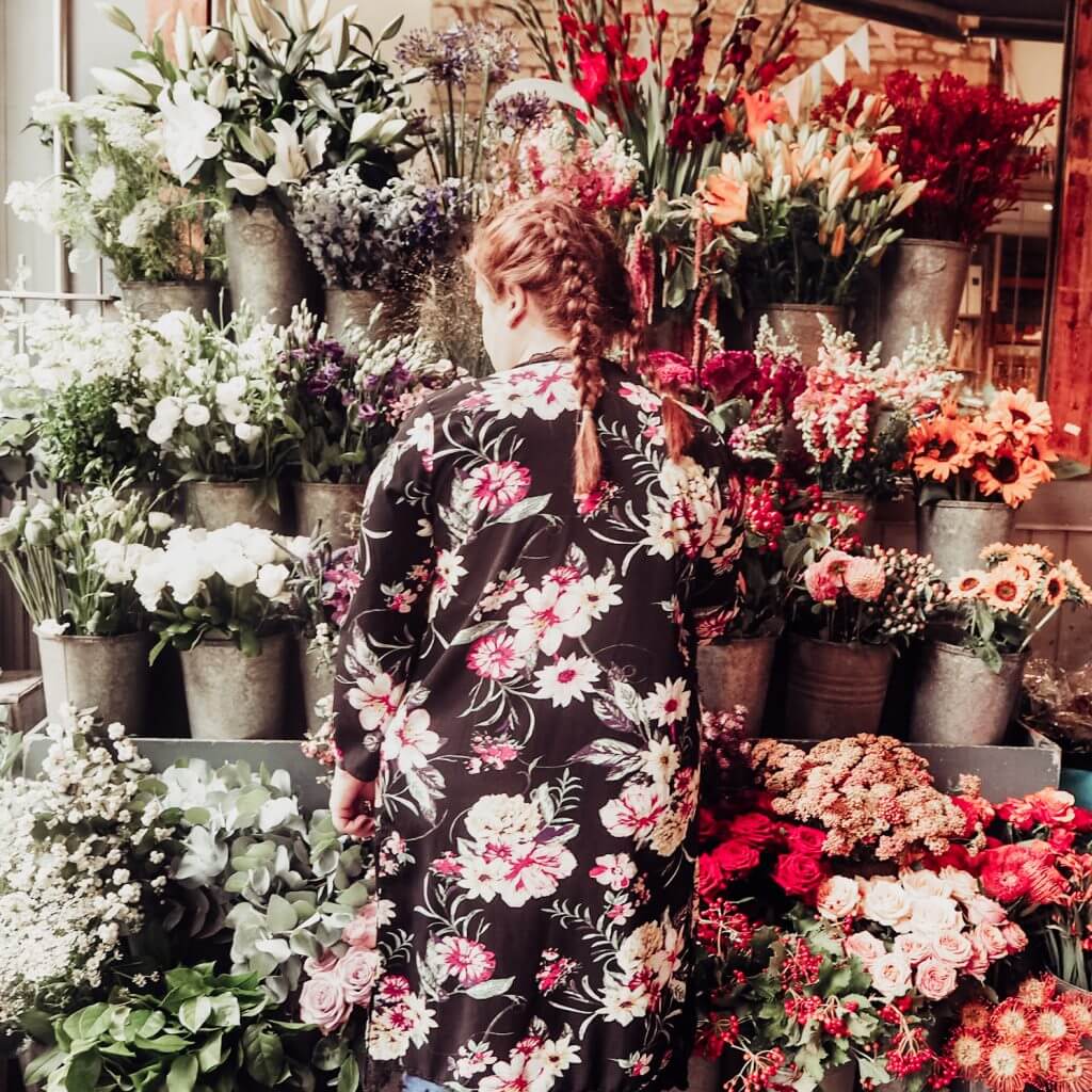Woman in a floral dress standing in front of a flower stand in Bath UK