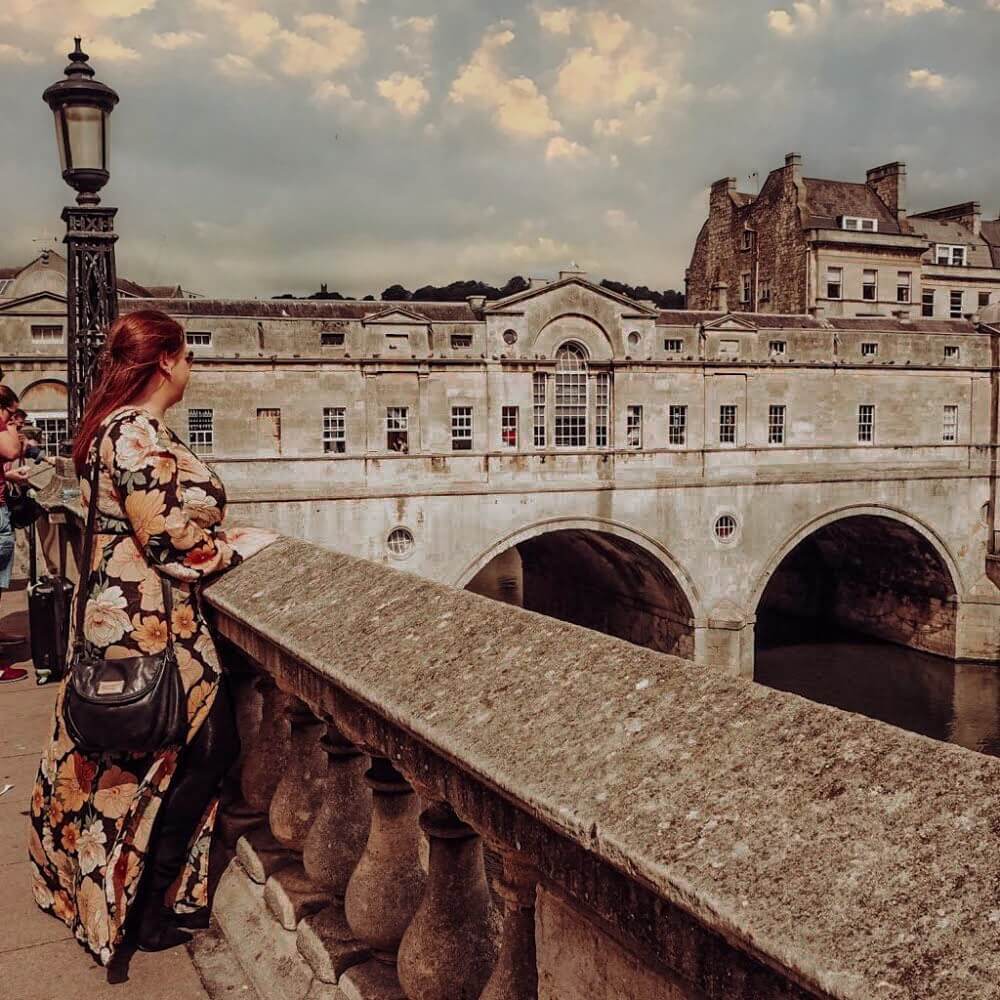 Woman in a floral dress looking over the Pulteney Bridge in Bath UK
