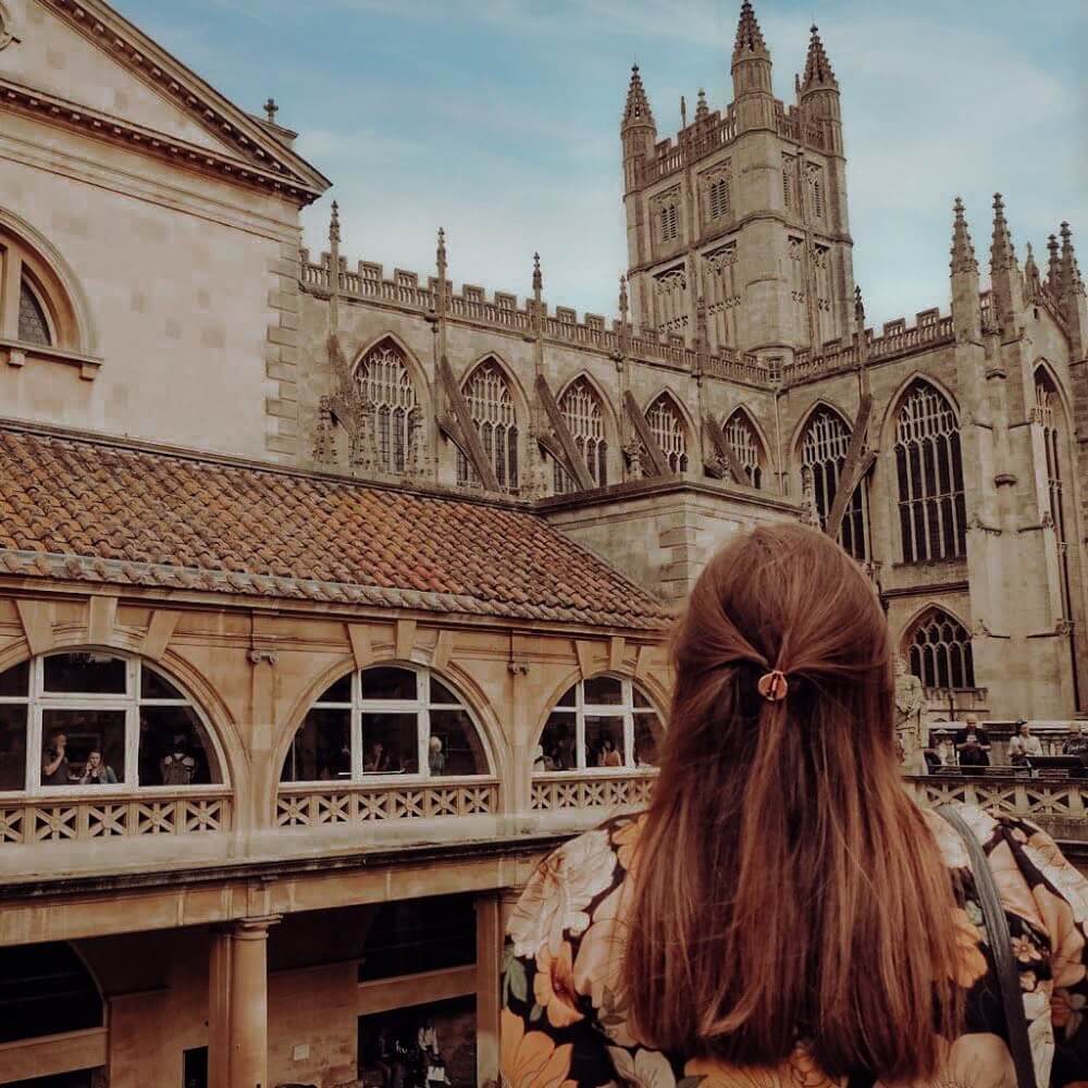Woman with red hair looking at the Romn Baths in Bath city UK