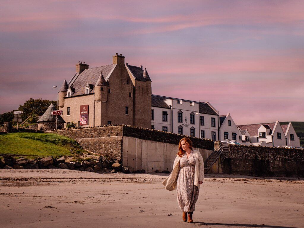 Woman walking on the beach in front of Ballygally castle in Antrim Ireland
