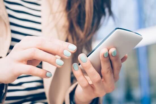 Girl looking at her phone wearing blue nail polish