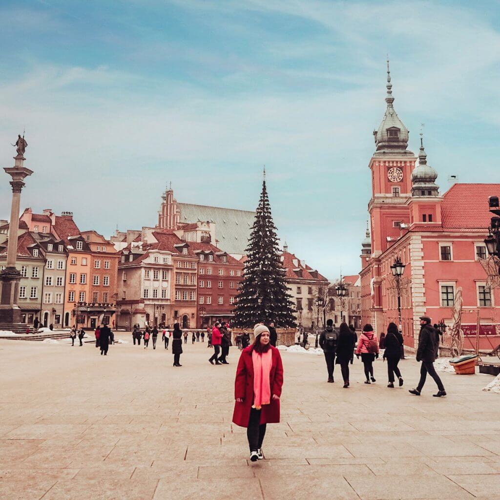 Woman wearing a red coat and pink scarf in Warsaw's main square at Christmas