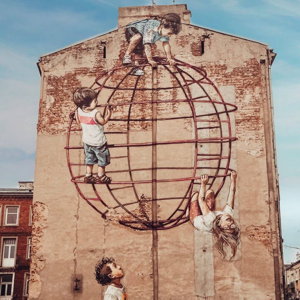 Street Art in Warsaw. Image of 3 children at a Playground Stalowa 51 painted on the side of a building.