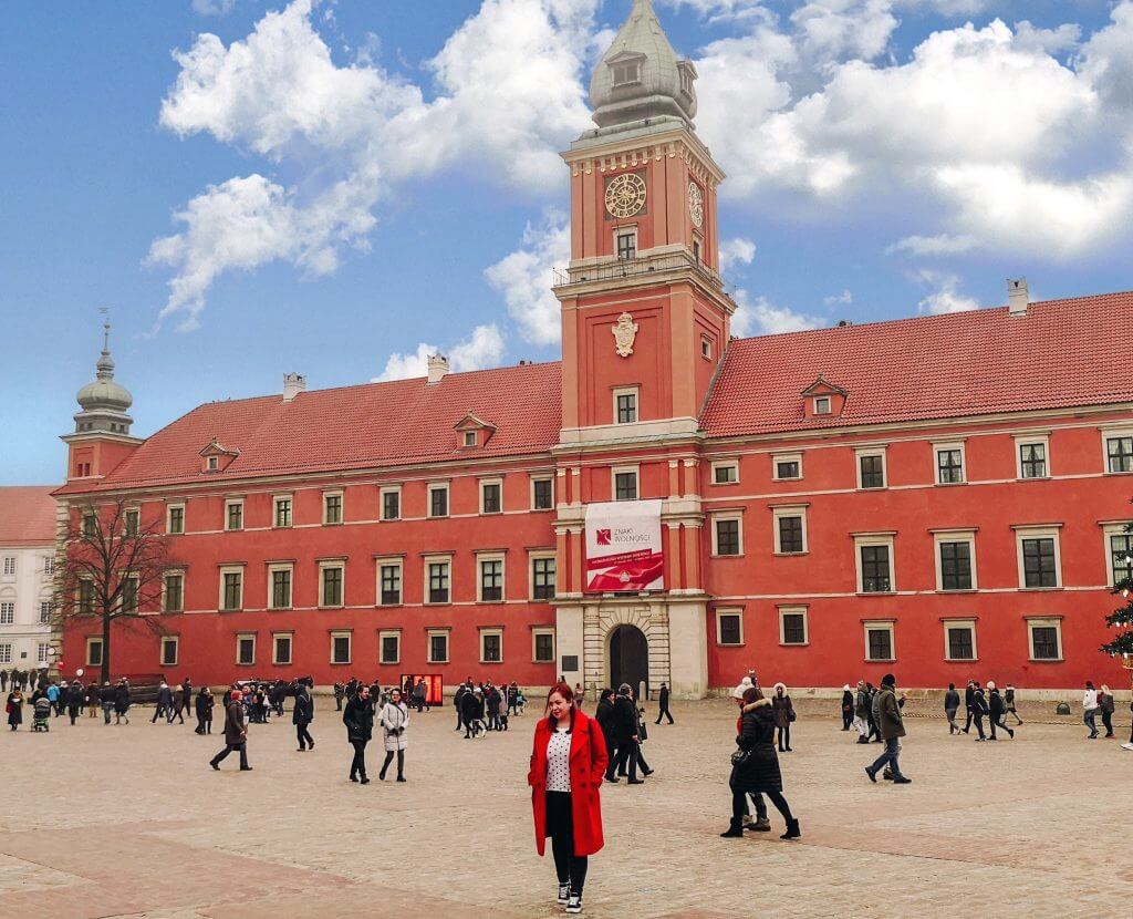 Woman in a red coat walking away from Warsaw Palace
