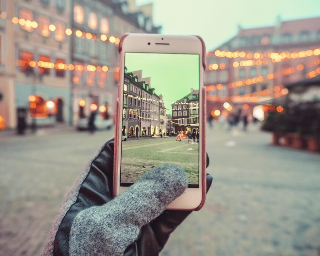 Woman taking a picture of Warsaw old town square on her phone