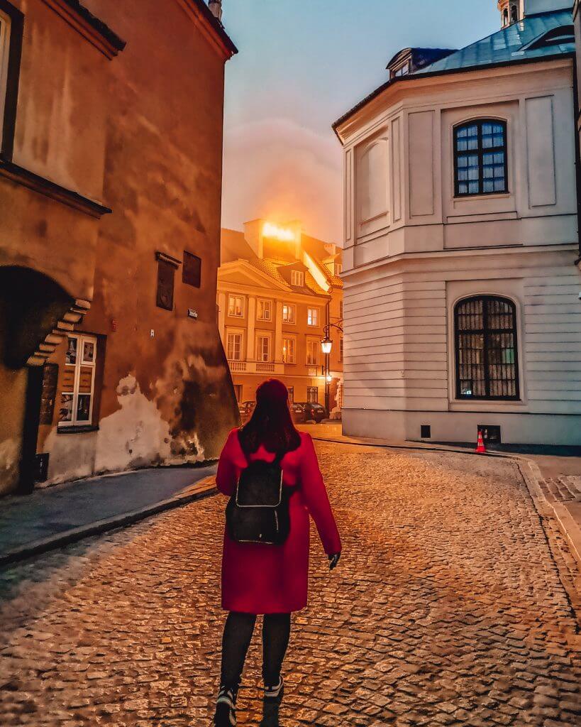 Woman walking along the cobbled alleyways of Warsaw at dusk