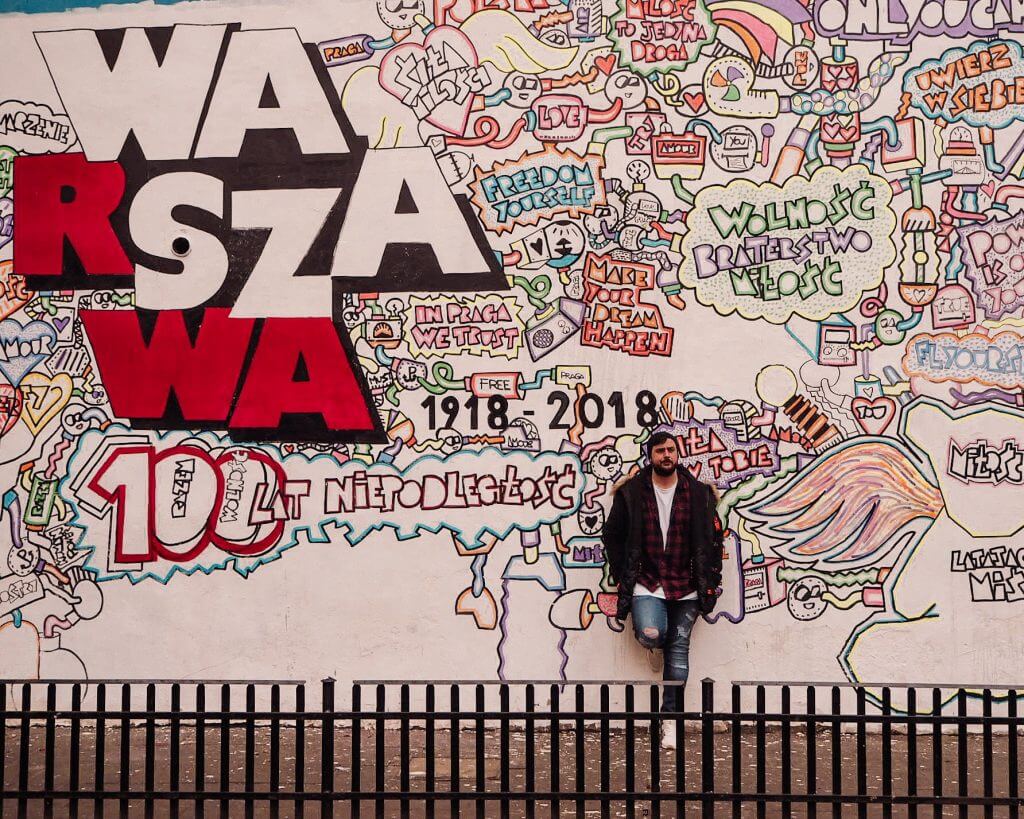 Man leaning against a wall of graffiti in Warsaw Poland