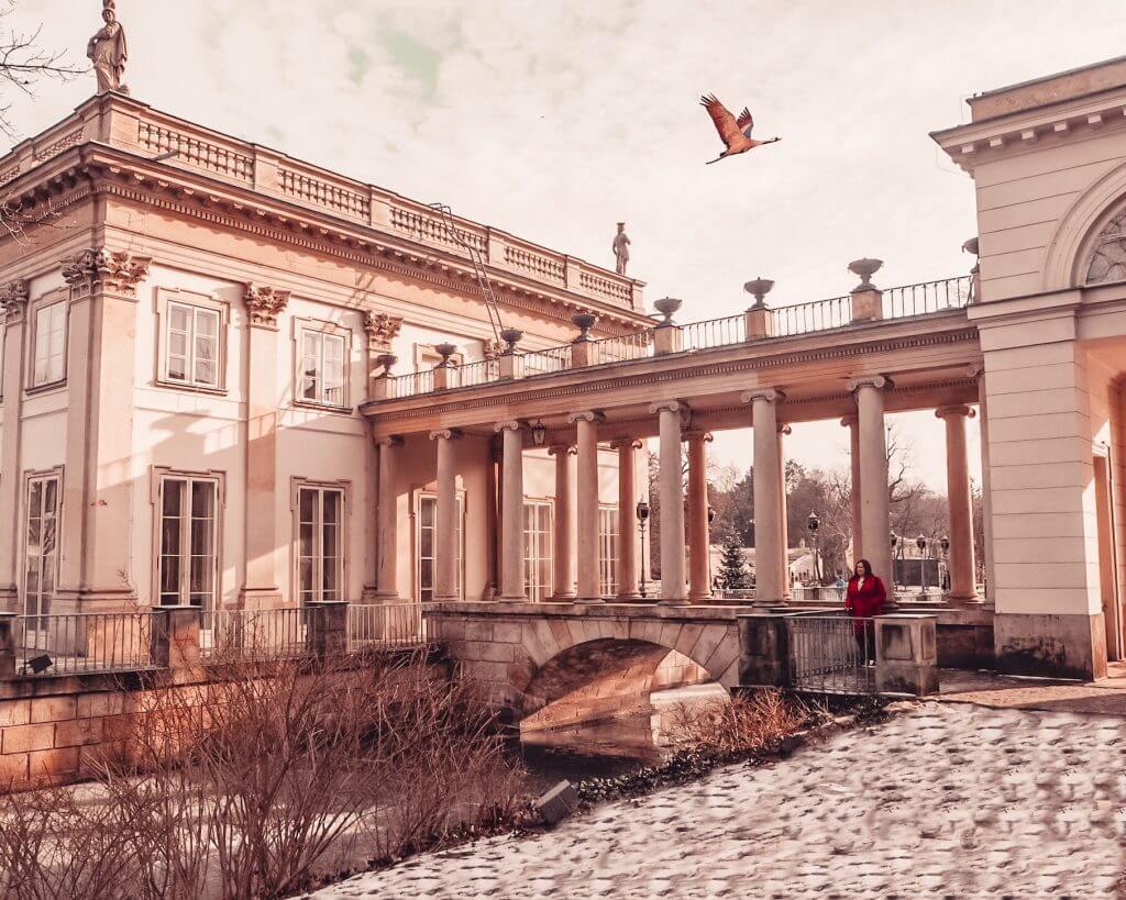 Woman in a red coat standing on a bridge in Warsaw, Łazienki Park