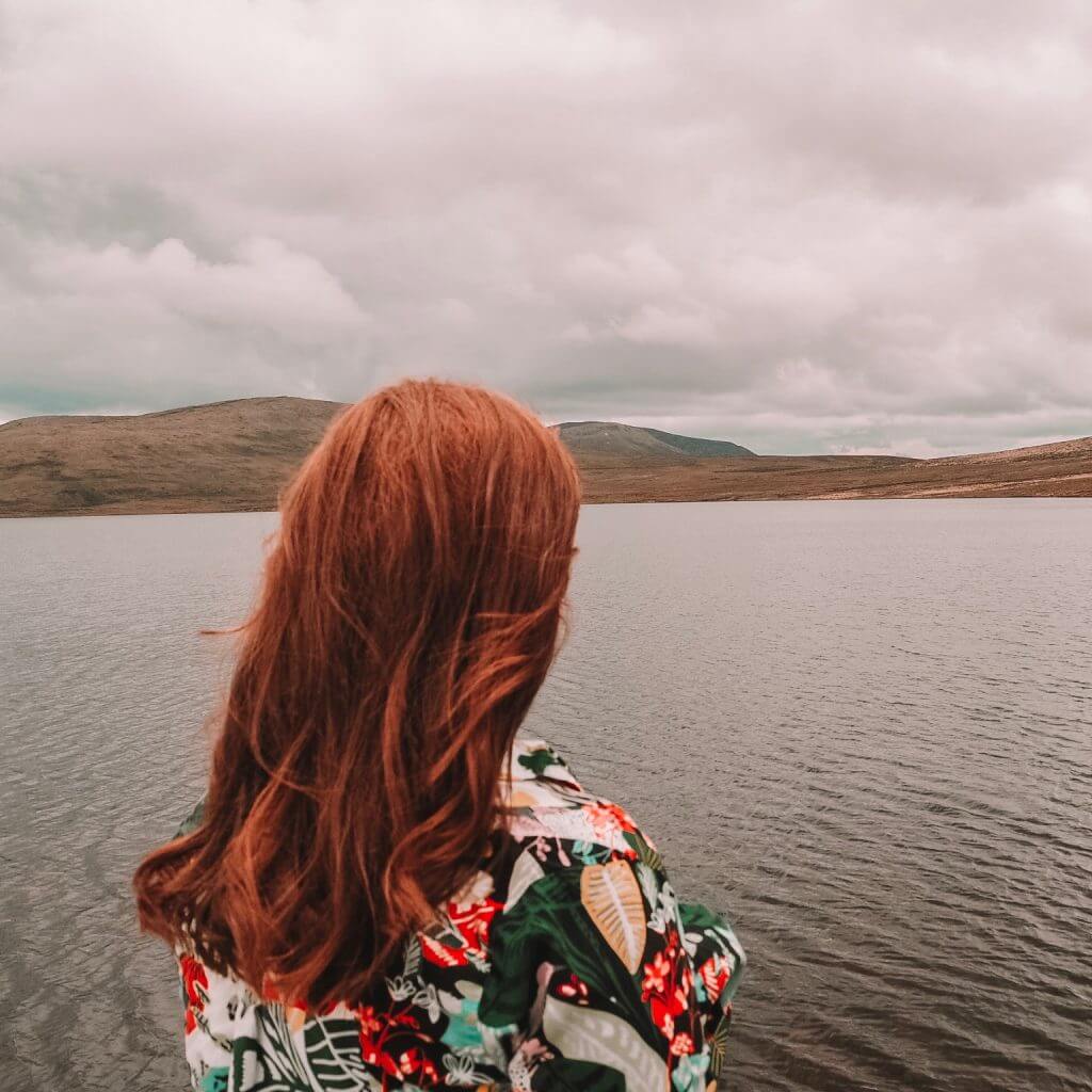 girl with red hair looking at a lake in northern ireland