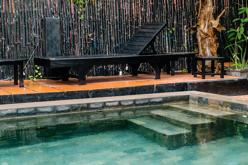 Black bench beside a swimming pool