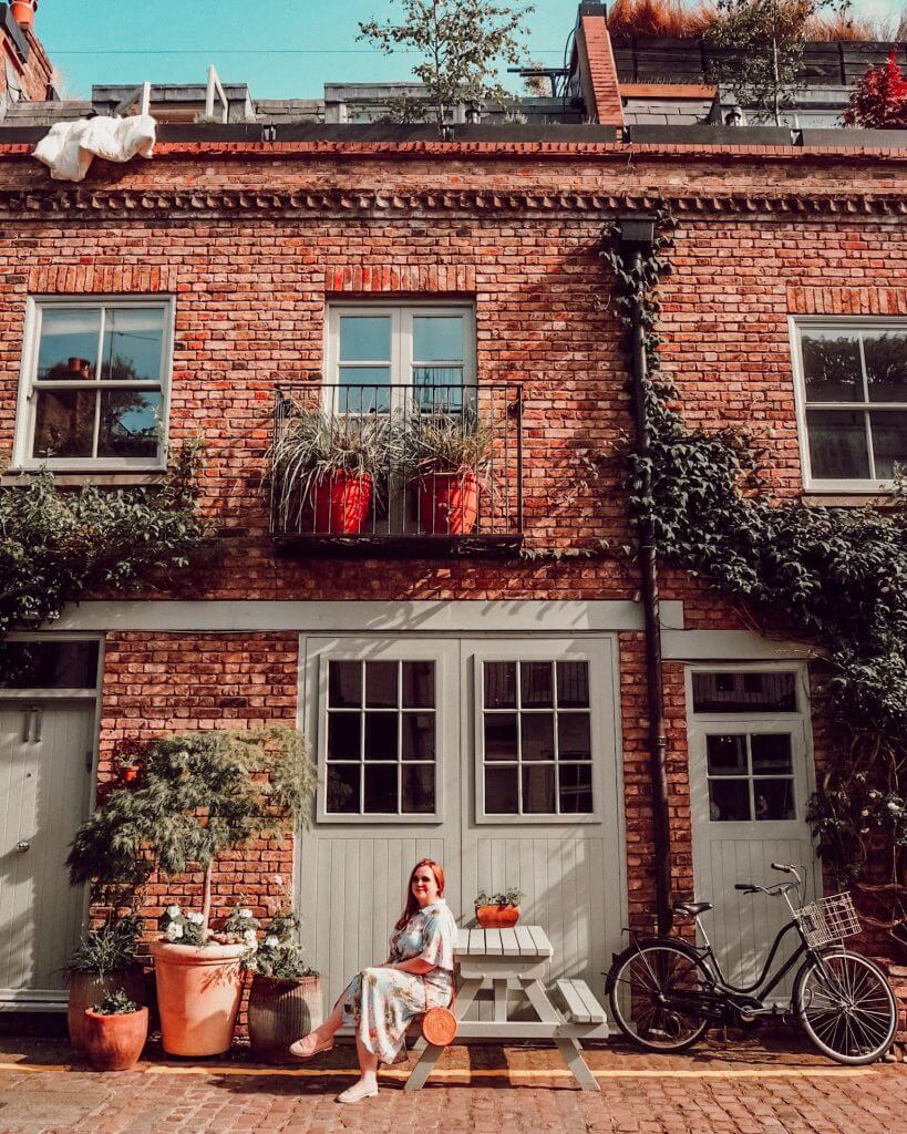 Woman sitting at a bench at St Luke's Mews in Notting Hill, London.