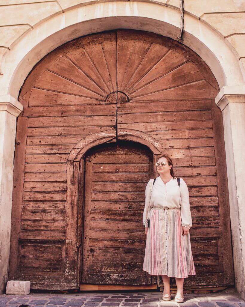 Woman standing in front of a brown doorway in Brasov Transylvania Romania