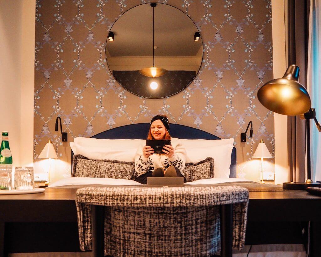 Girl in Christmas jumper sitting on the bed of her hotel romm in Tortue Hotel Hamburg Germany.