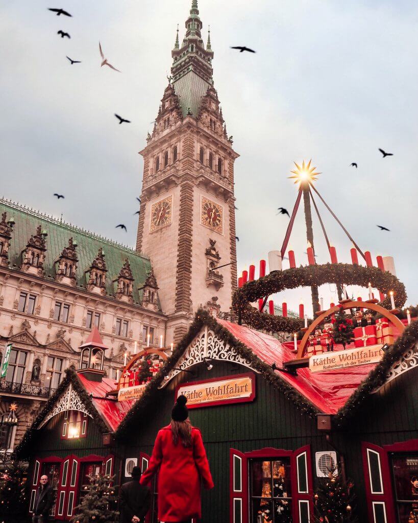 Girl in red cost standing in front of Rathausmarkt Hamburg Christmas market in the city hall town square