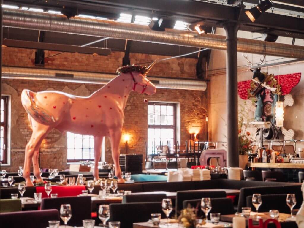 Quirky restaurant design including a pink unicorn at Bullerei restaurant Hamburg a great place to grab a bite to eat during your weekend in Hamburg