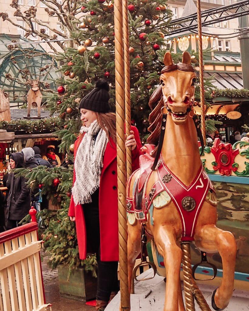 Girl in red coat and black hat on a carousel at Hamburg Christmas Markets
