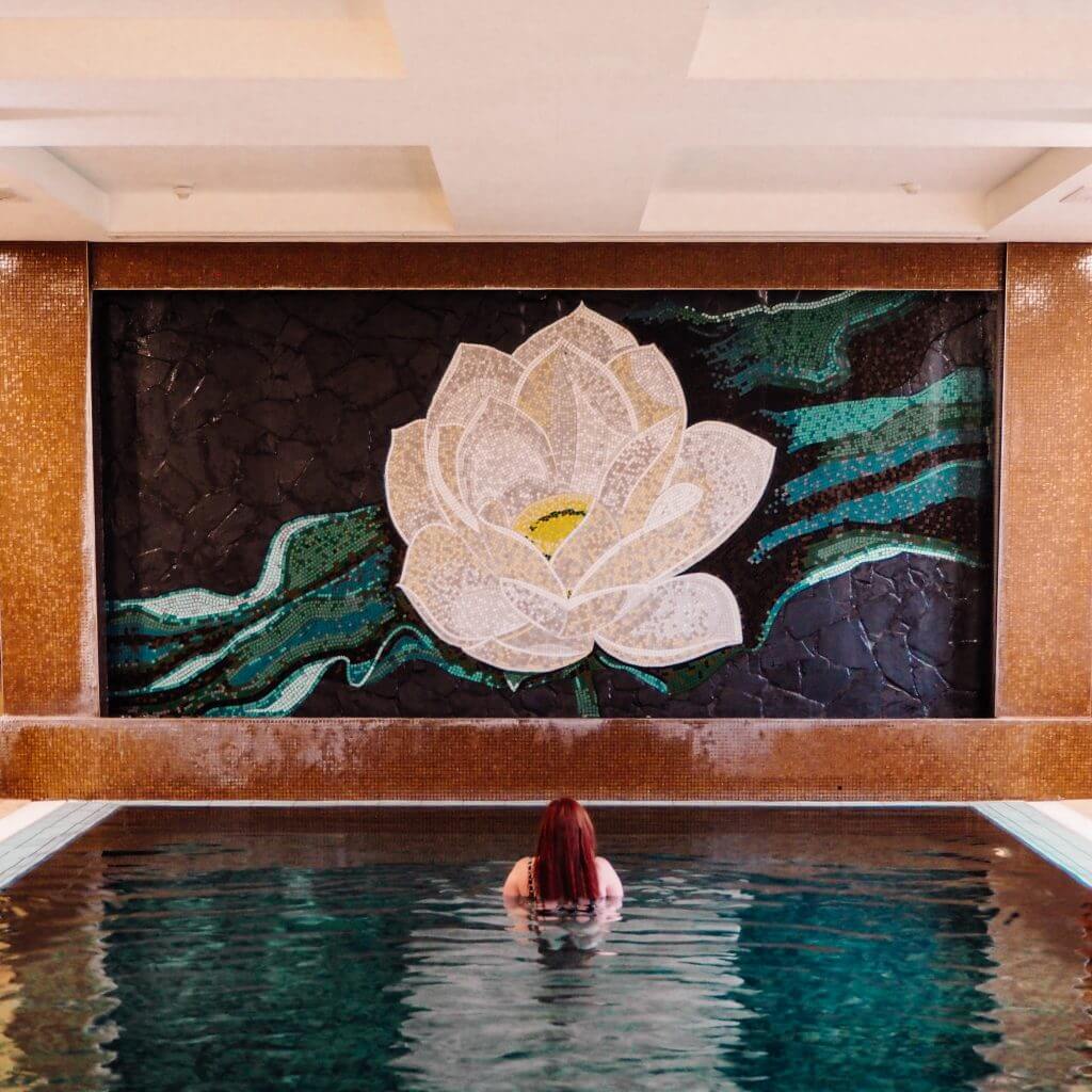 Travel blogger All about RosaLilla in the infinity pool at the Thai spa in Lough Erne. There is a large flower mural on the wall.