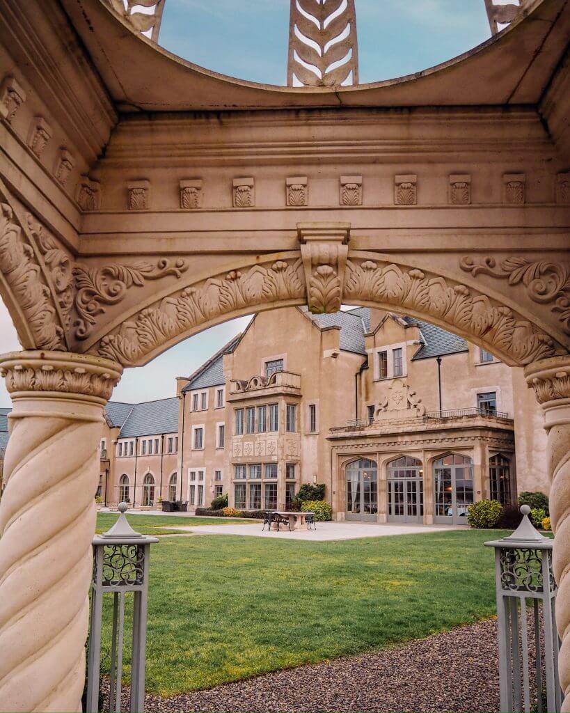 Country Manor house style of the main hotel building of Lough Erne viewed through the archway of an ornate gazebo on the grounds of the hotel.