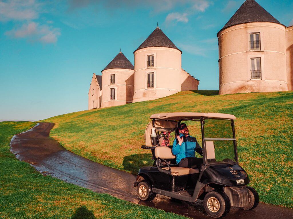 Male golfer in a blue top driving a golf cart in Lough Erne.
