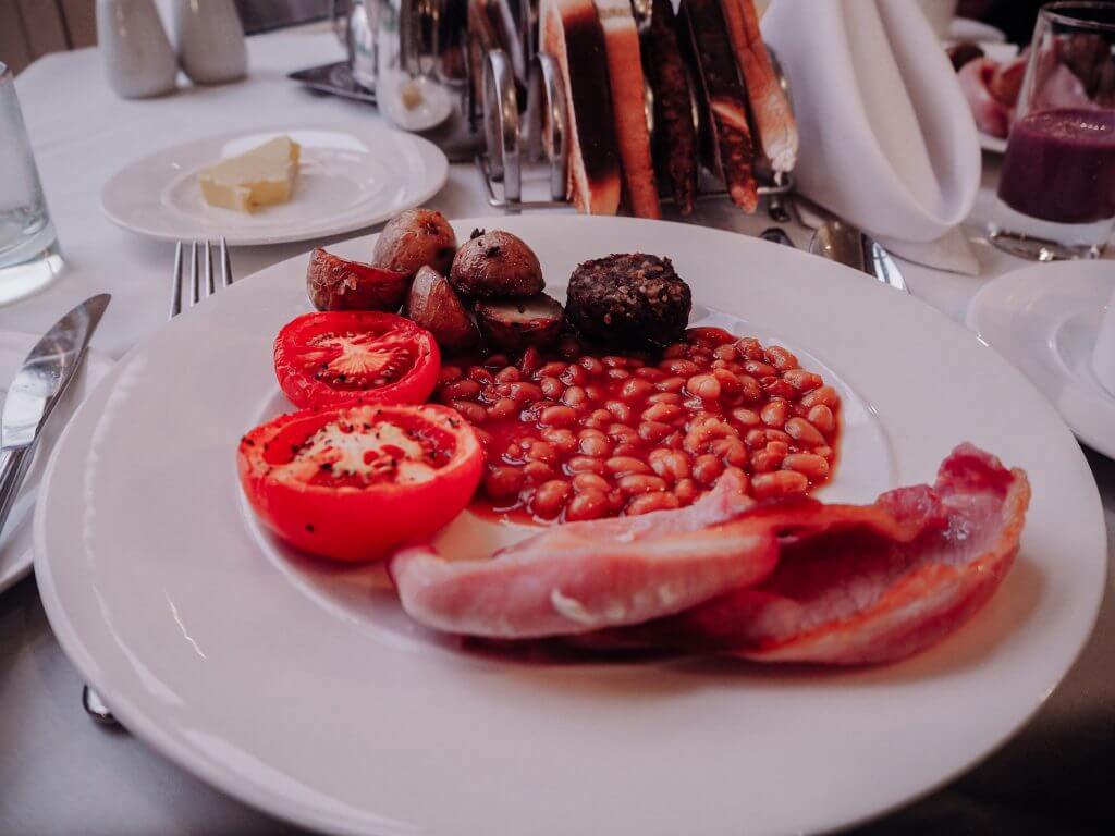 Irish breakfast with rashers, beans, tomatoes and white pudding on a plate.