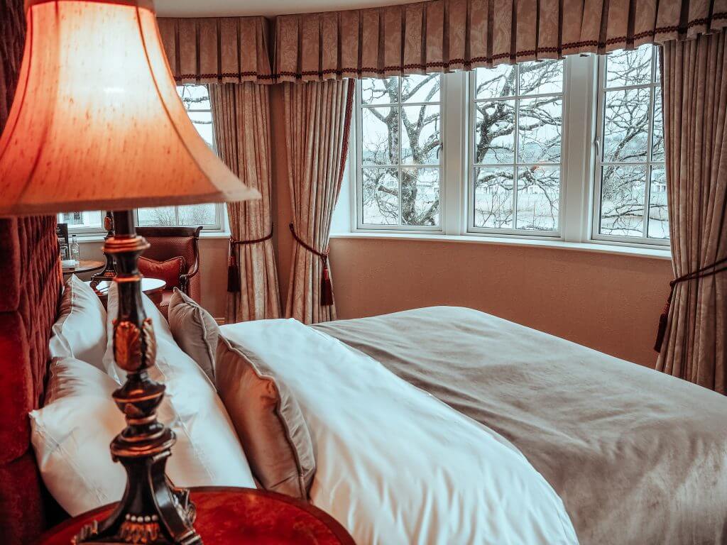 The Dovecote suite at Lough Erne resort in Northern Ireland containing a large double bed with sumptuous bedding and soft lighting.