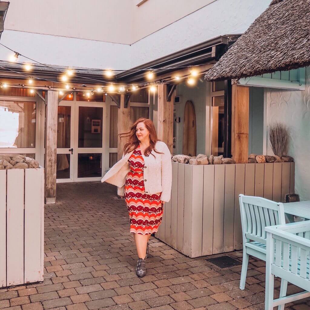 Woman walking through a seaside restaurant in County Clare Ireland with fairy lights twinkling overhead