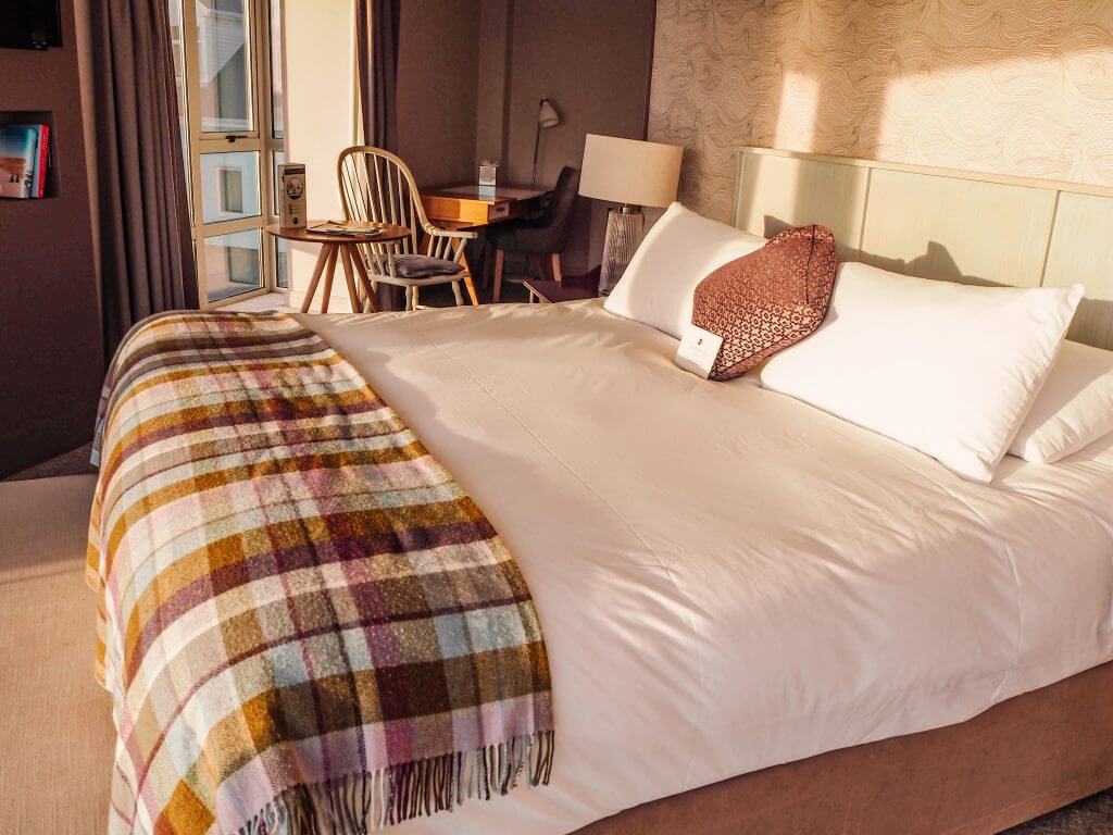 Large King size bed with tartan wool blanket at Armada Spanish Point Hotel