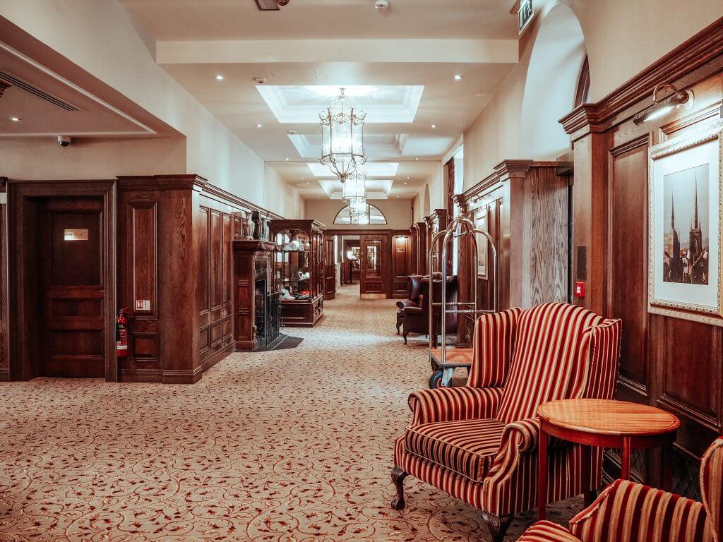 Reception area of a hotel with striped red and orange armchairs and wooden paneling on the walls