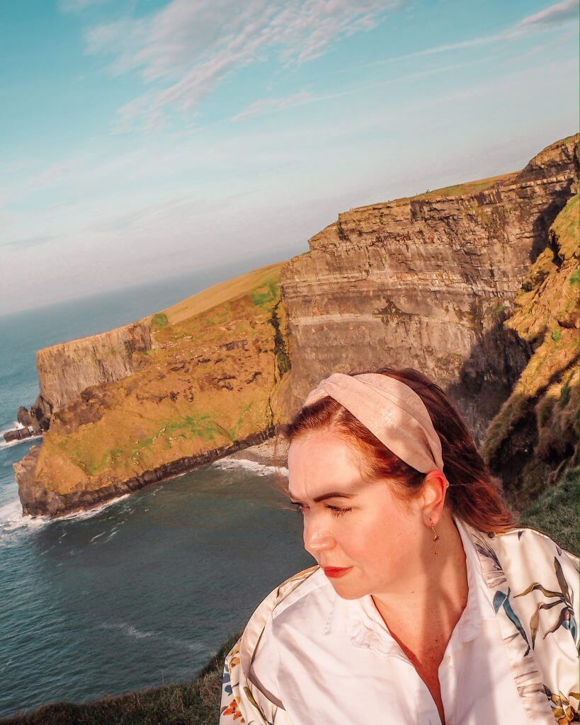 Woman with red hair watching the sunset at the Cliffs of Moher Ireland