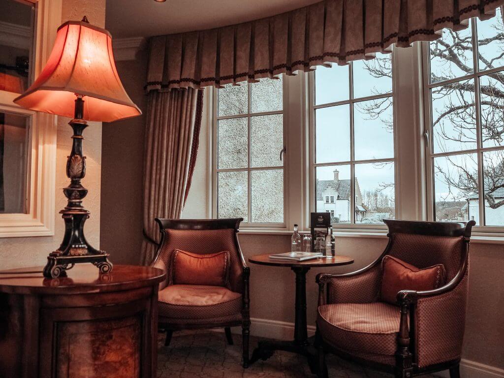 Corner of The Dovecote suite at Lough Erne resort with a seated area containing two armchairs and a reading lamp.