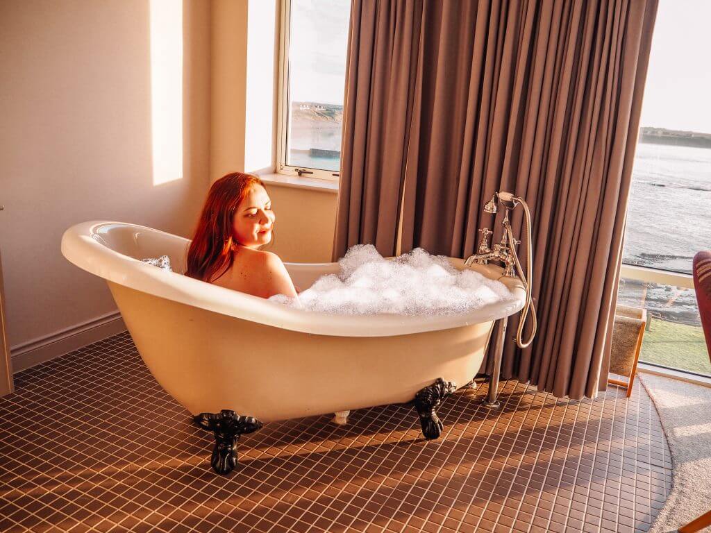 Woman enjoying a bubbl bath at sunset in a luxury hotel in Ireland