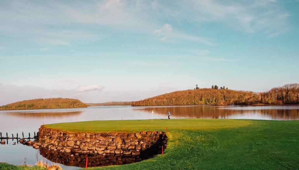 Male golfer playing the signature hole 10 at Lough Erne golf and spa resort.