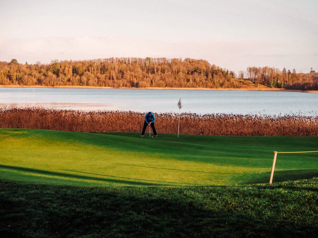 Male Golfer in blue top putting a ball on the first hole of Lough Erne Golf Resort.