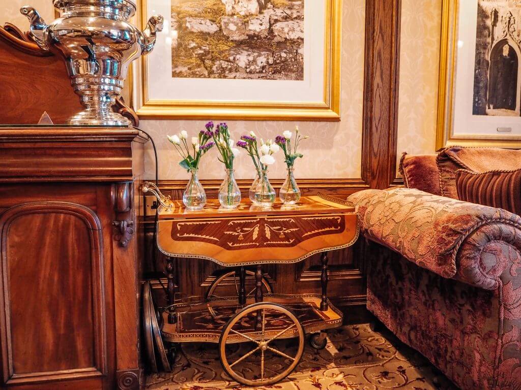 Decorative trolley in Hotel lobby with vases of flowers on top.