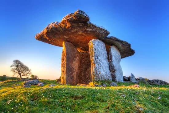 A large flat stone being held up by four vertical stones. A traditional burial site of Polnabrone Dolmen in The Burren in Ireland