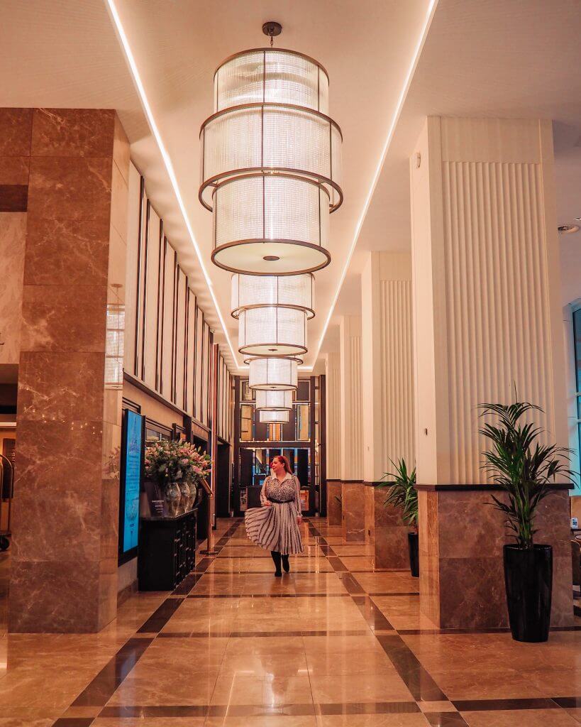 Woman in a white dress walking through the reception hall at Grand Central Hotel Belfast an instagram spot belfast.