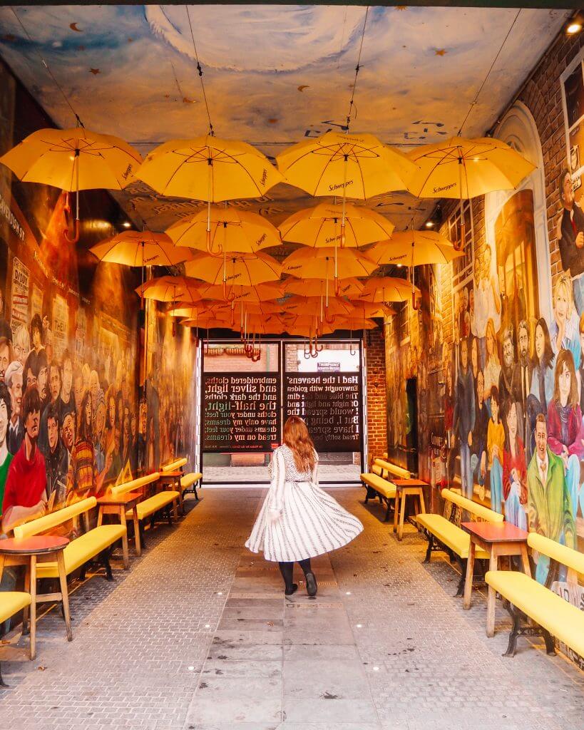 Woman in a white dress twirling under an umbrella sky in one of Belfast's best Instagram spots