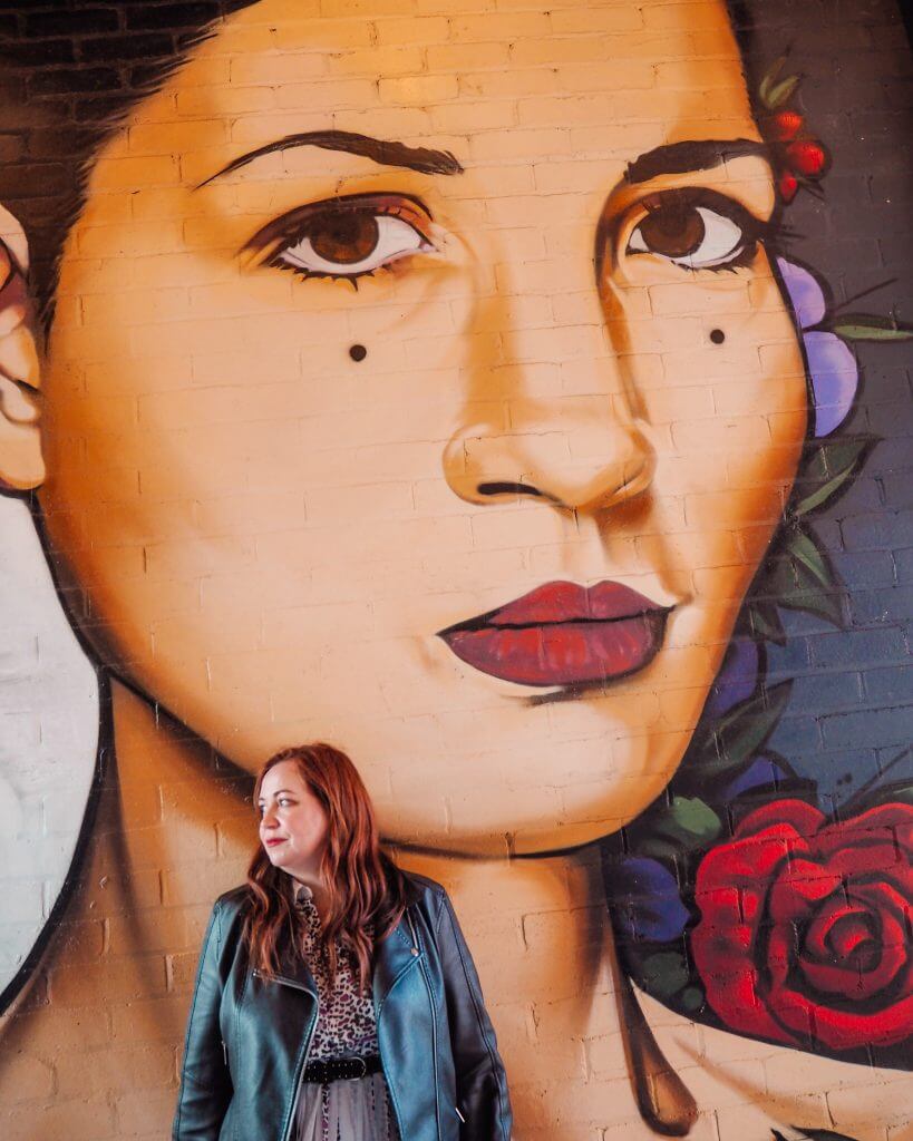 Woman leaning against some street art on the streets of Belfast. A great instagram spot Belfast