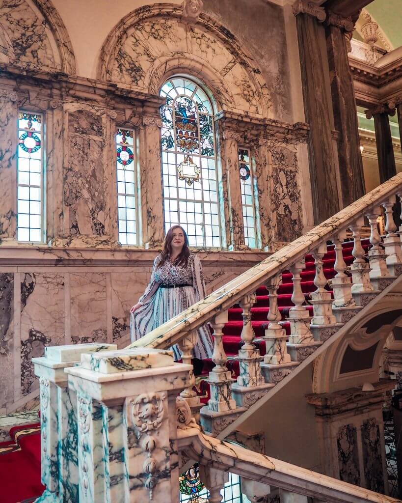Woman in a white dress walking down the marbled staircase of Belfast City Hall
