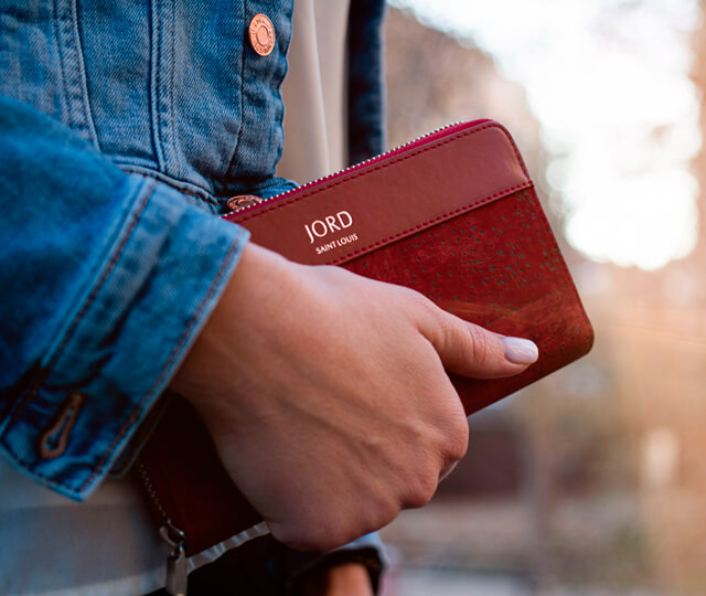 Woman wearing a denim jacket holding a red vegan leather wallet