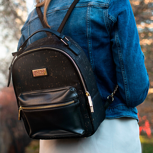 Woman in a denim jacket wearing a black jord vegan leather backpack