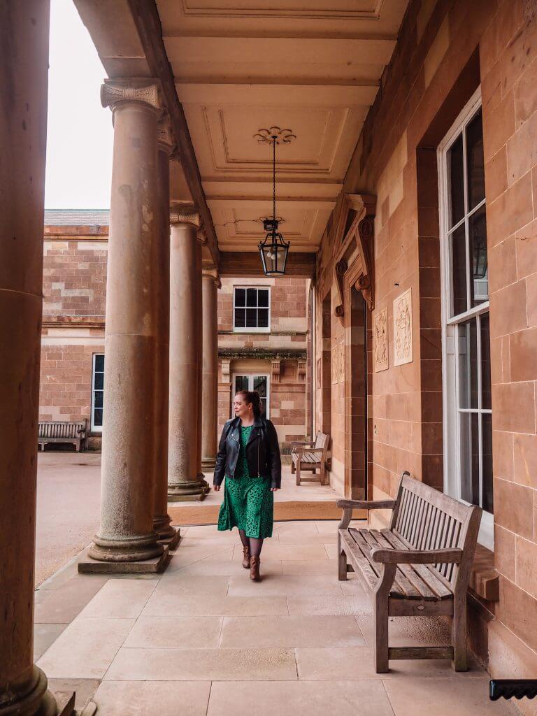 Woman in a green dress walking under the arches of Hillsborough Castle Northern Ireland