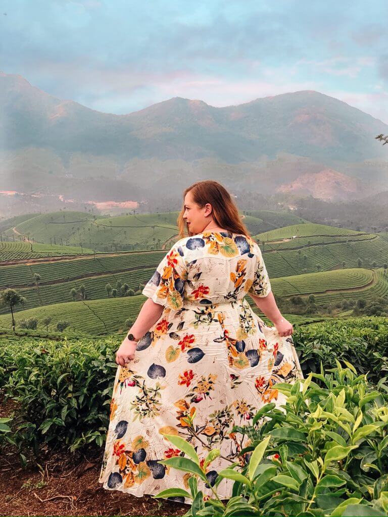 Woman in a floral dress standing among the tea plantations in Munnar Kerala India
