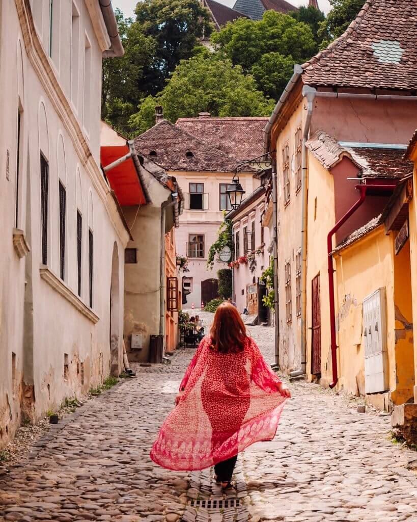 Woman walking around the colourful streets of Sighisoara Romania