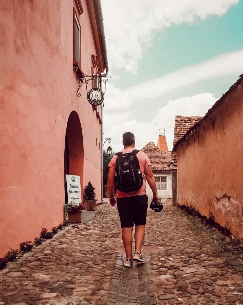 Man walking with his camera through the cobbled streets of Sighisoara Romania