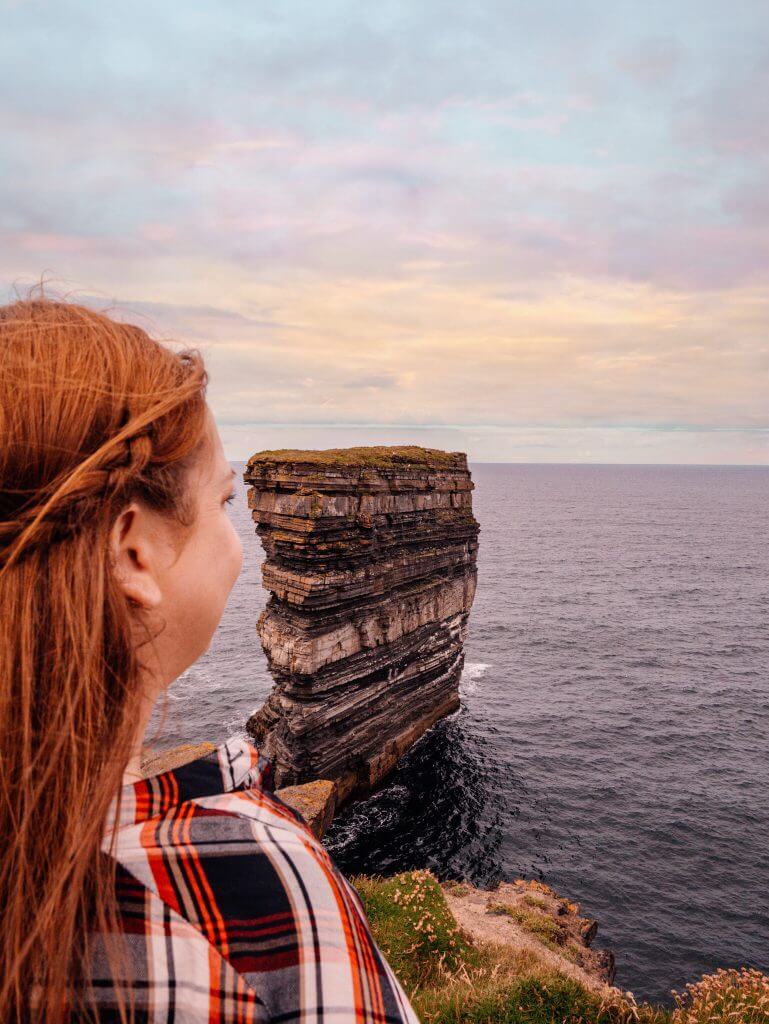 Woman looking out at Dun Briste sea stack at Downpatrick Head in county Mayo