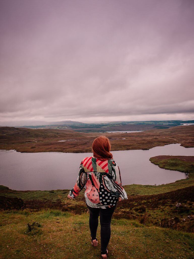 Woman wearing a colourful yop overlooking the mountain views at Lough Salt in County Donegal Ireland. Staycation Ireland Ideas